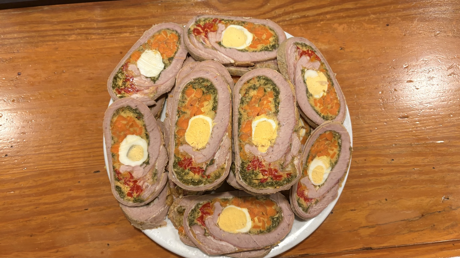 Matambre arrollado casero del Bar Sonora con huevo, zanahoria y verduras sobre una mesa de madera